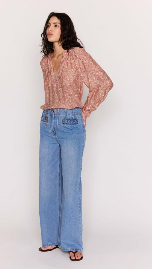 Model wearing a Red Floral Peasant Blouse with billowed sleeves and V neckline, paired with wide-leg jeans.