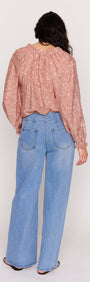 Back view of model wearing a Red Floral Peasant Blouse with billowed sleeves and wide-leg jeans.