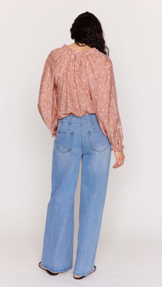 Back view of model wearing a Red Floral Peasant Blouse with billowed sleeves and wide-leg jeans.
