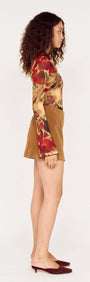 Side view of a model wearing a Red Floral Sheer Mesh High Neck Top with brown shorts.