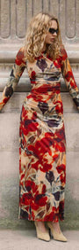 Woman in a Red Floral Sheer Mesh Midi Dress poses against a stone wall, showcasing bold floral patterns and long sleeves.