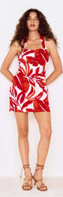 Red Palm Print Halter Neck Mini Dress displayed by a model with long curly hair, posing in a vibrant red and white floral design.