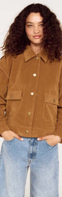 Model wearing a Relaxed Fit Faux Suede Jacket in brown with large pockets and a collared neckline, paired with blue jeans.