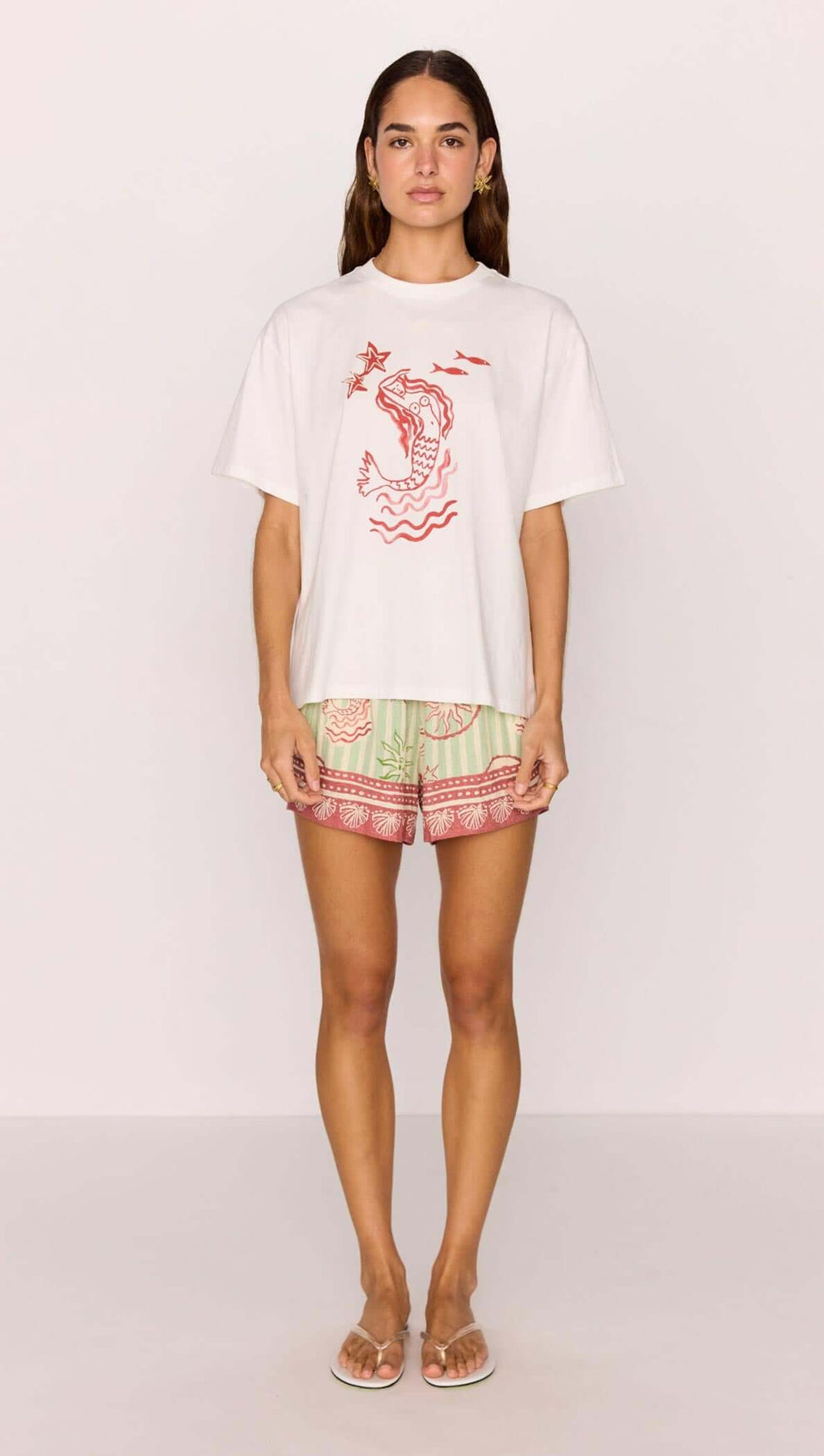 Model wearing a Cotton Mermaid Print T-Shirt with mermaid graphic paired with colorful shorts.