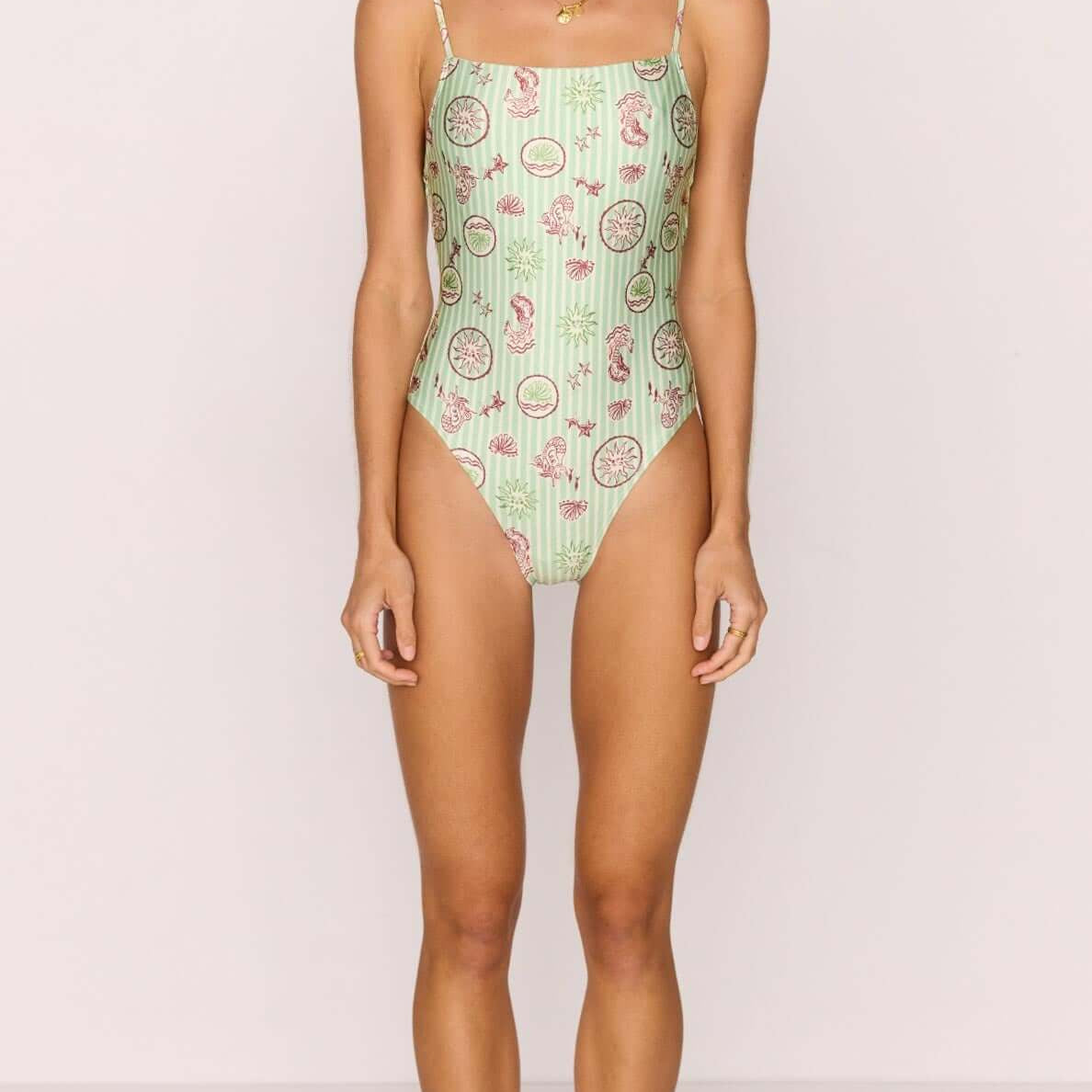 Green Stripe Printed Low-Back One Piece Swimsuit on a model showcasing the exclusive shell and sea motif.
