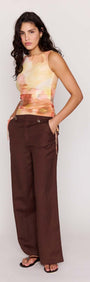 Model wearing the Sunset Tonal Drawstring Mesh Top with brown pants, showcasing its vibrant sun-washed print and adjustable side drawstrings.
