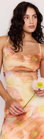 Model wearing a Sunset Tonal Mesh Maxi Dress, holding a flower, showcasing the vibrant floral print.