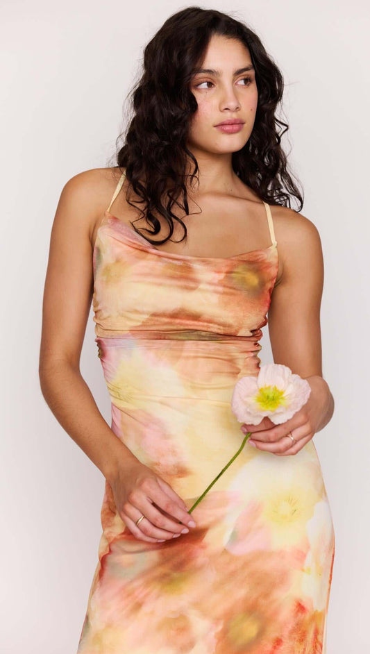 Model wearing a Sunset Tonal Mesh Maxi Dress, holding a flower, showcasing the vibrant floral print.