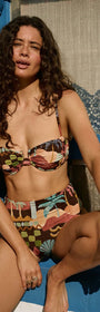 Model wearing Vintage Coastal Print High Waisted Bikini Bottom with colorful patterns in beach setting.
