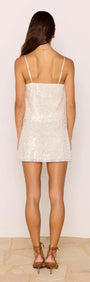 Back view of a woman wearing a White Sequin Mini Skirt with a fitted waistband and spaghetti straps.