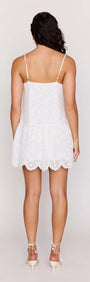 View of the back of the White Broderie Anglaise Mini Dress, showcasing its sleeveless design and scalloped hem.