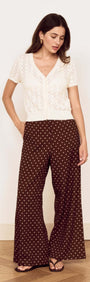 Model wearing a White Cotton Pointelle Knit Top with brown polka dot pants, highlighting a chic layered look.