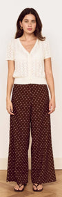 Model wearing a White Cotton Pointelle Knit Top with polka dot trousers, showcasing a stylish, feminine look.