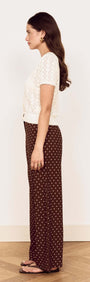 Model showcasing the White Cotton Pointelle Knit Top paired with brown polka dot pants, side view.