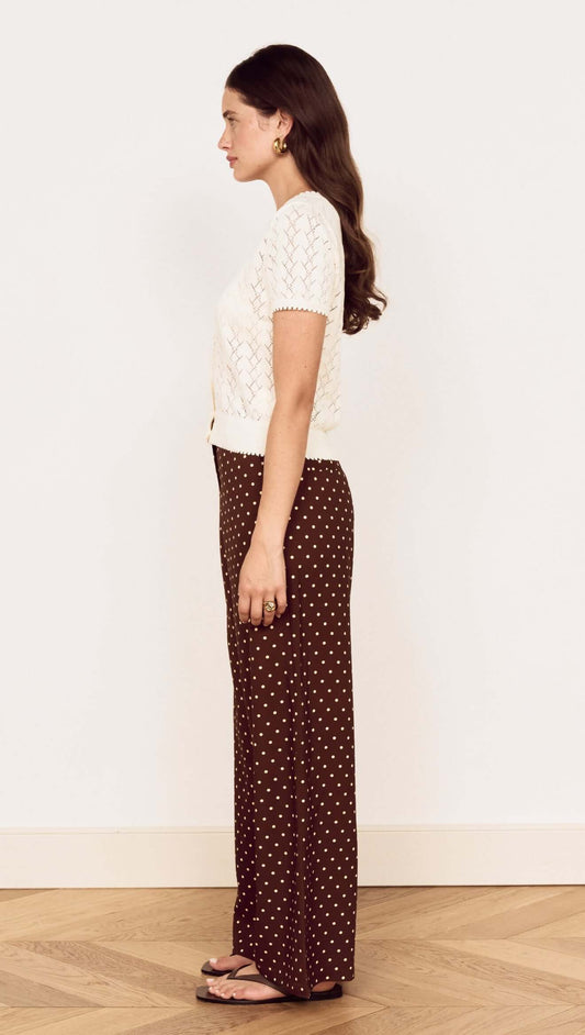 Model showcasing the White Cotton Pointelle Knit Top paired with brown polka dot pants, side view.