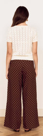 Back view of a model wearing a White Cotton Pointelle Knit Top with polka dot wide-leg pants.