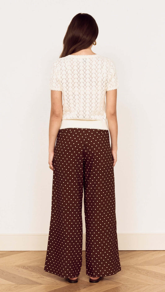 Back view of a model wearing a White Cotton Pointelle Knit Top with polka dot wide-leg pants.