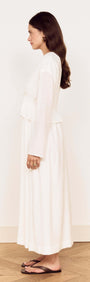 Side view of a woman wearing a White Crinkle Tie Front Midi Dress with relaxed long sleeves and a layered peplum.