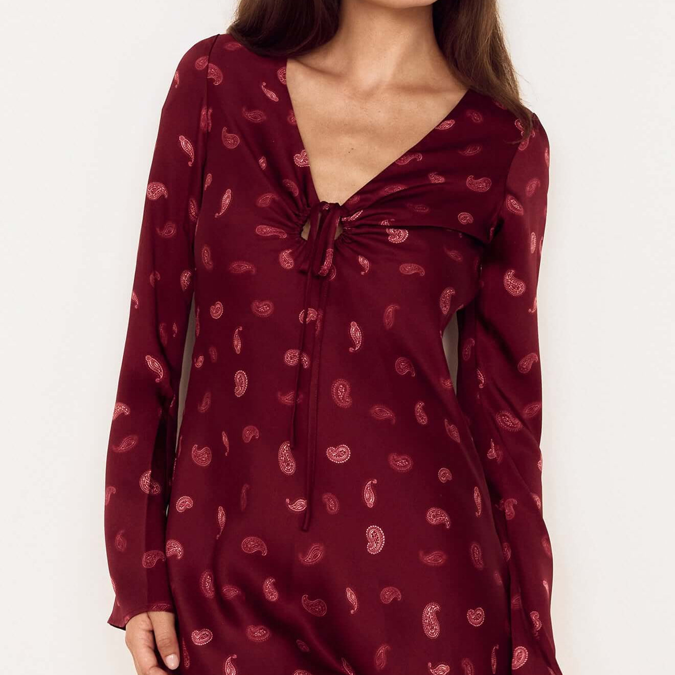 Model wearing the Wine Satin Paisley Knot Front Bias Mini Dress featuring a V-neckline and flared sleeves.