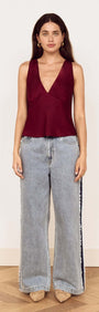 Model wearing the Wine Satin V-Neck Cami Top with wide-leg jeans, showcasing elegant evening style.