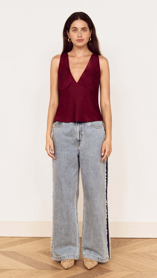 Model wearing the Wine Satin V-Neck Cami Top with wide-leg jeans, showcasing elegant evening style.
