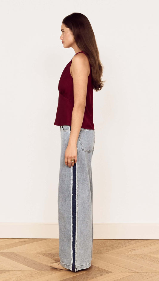 Model showcasing the Wine Satin V-Neck Cami Top paired with wide-leg jeans from a side view.