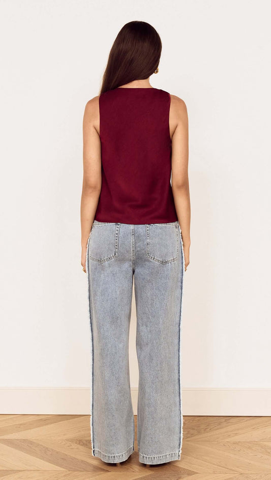 Back view of a model wearing the Wine Satin V-Neck Cami Top with wide leg denim jeans.