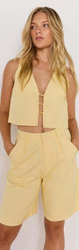 Model wearing a butter yellow high-waist Bermuda short and matching cropped top, stylish summer outfit.