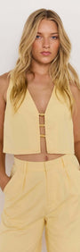 Model wearing a stylish butter yellow cropped top with a V neckline and two front buckle details.