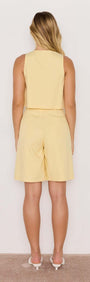 Back view of a model wearing Butter Yellow High-Waist Bermuda Shorts with a matching top, showcasing a breezy summer outfit.