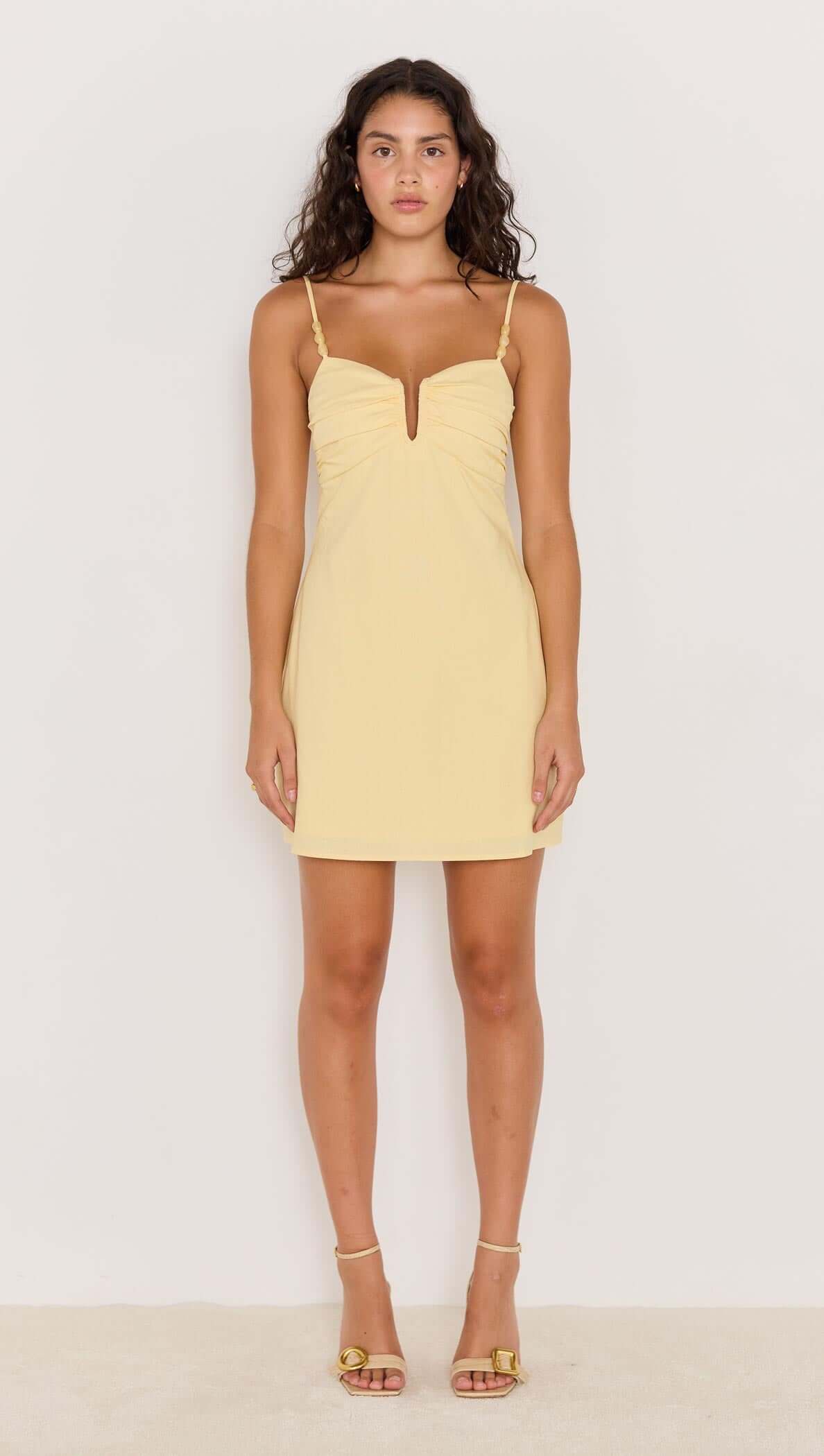 Butter yellow mini dress with bead detail, featuring a V-neckline and spaghetti straps worn by a model.