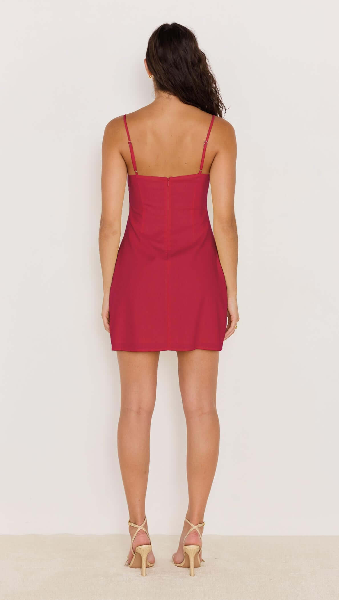 Back view of a red mini dress with bead detail, showcasing a fitted silhouette and adjustable spaghetti straps.
