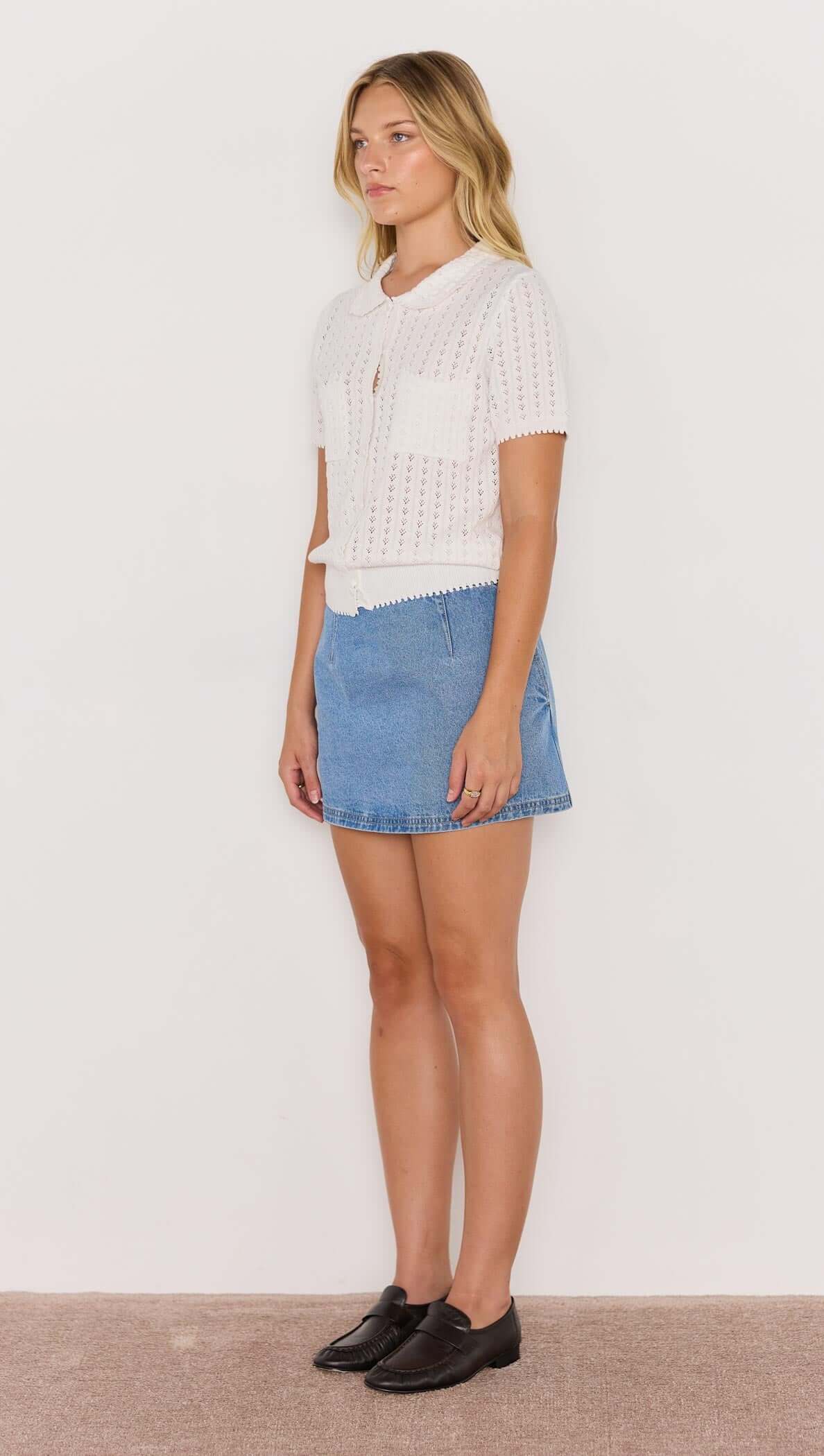 Model wearing a white French Pointelle short sleeve knit top paired with a denim skirt.