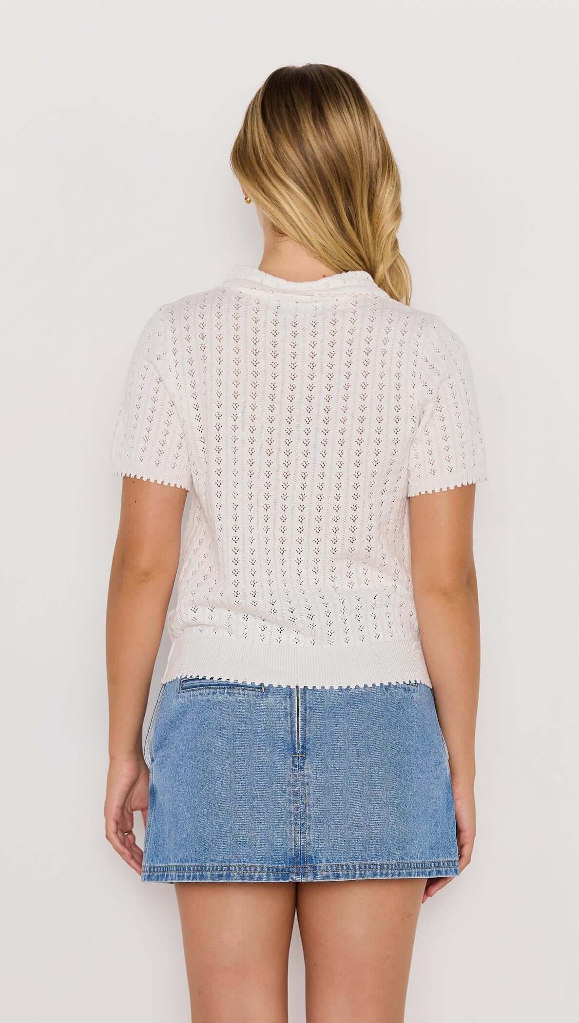 Model wearing a white French Pointelle short sleeve knit top paired with a denim skirt.