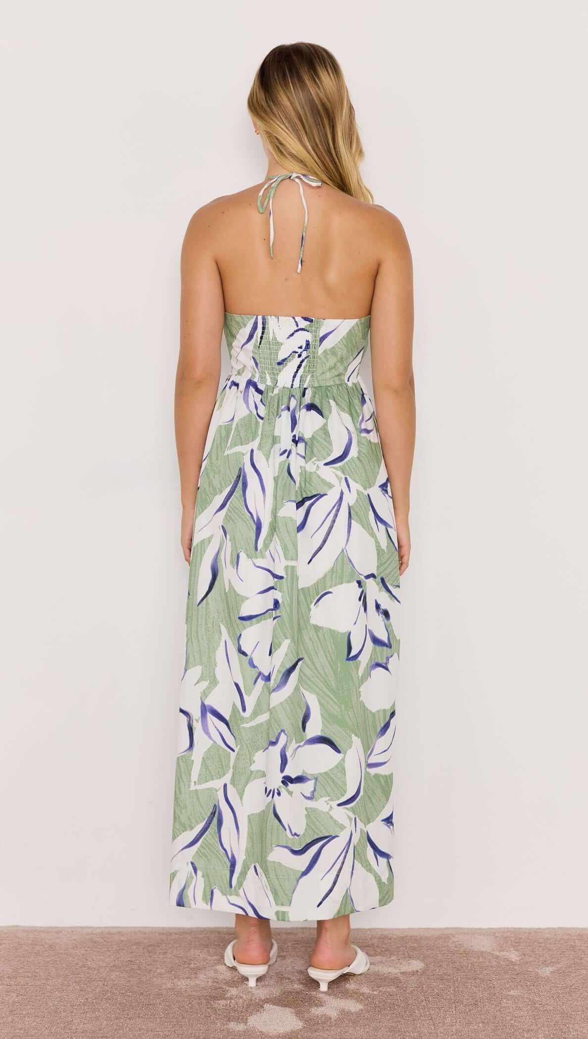 Back view of a woman wearing a Green &amp; White Floral Halter-Neck Midi Dress with a relaxed fit.