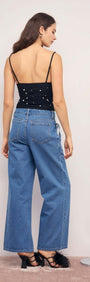 Back view of a model wearing a Pearl Embellished Black Mesh Crop Top with wide-leg denim pants.