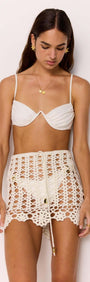 Model wearing Resort Crochet Knit Mini Skirt in White over swimwear, featuring scalloped hem and drawstring waist.