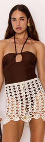 Model wearing the Resort Crochet Knit Mini Skirt in White over a brown swimsuit, showcasing summer beach style.