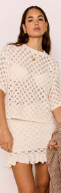 Model wearing a White Pointelle Knit Mini Skirt paired with a matching top and holding a textured shawl.