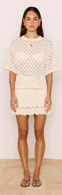 Woman wearing a White Pointelle Knit Mini Skirt and matching top, showcasing a casual summer outfit with a feminine design.