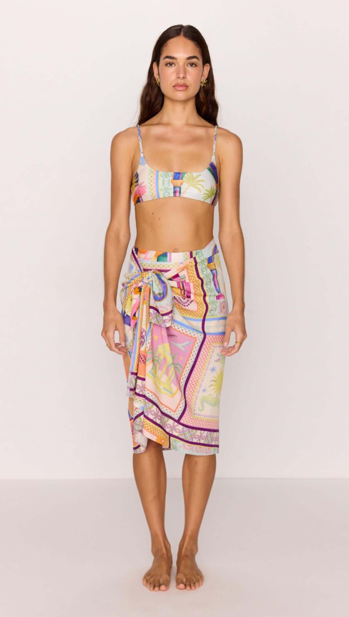 Model wearing a sarong in bold multicolour print with a matching bikini top, showcasing a stylish beach look.