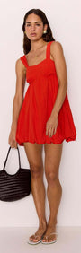 Model wearing Scarlett Red Bubble Mini Dress with a soft bubble hem and gathered bust, styled with a black bag.