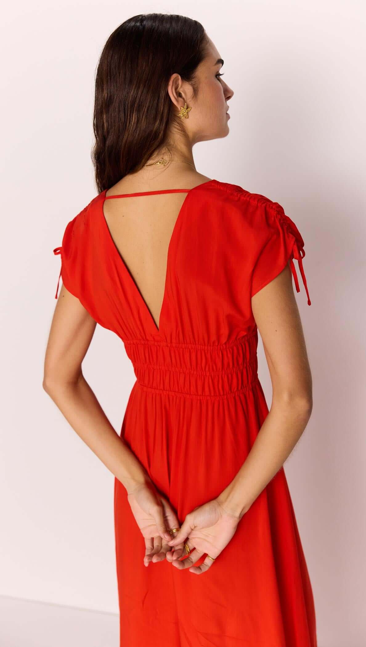 Rear view of model wearing the Scarlett V-Neck Midi Dress with Bead Detail, featuring a shirred waist and cap sleeves.