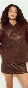 Model wearing a brown faux leather mini skirt and matching jacket, showcasing trendy fall fashion.