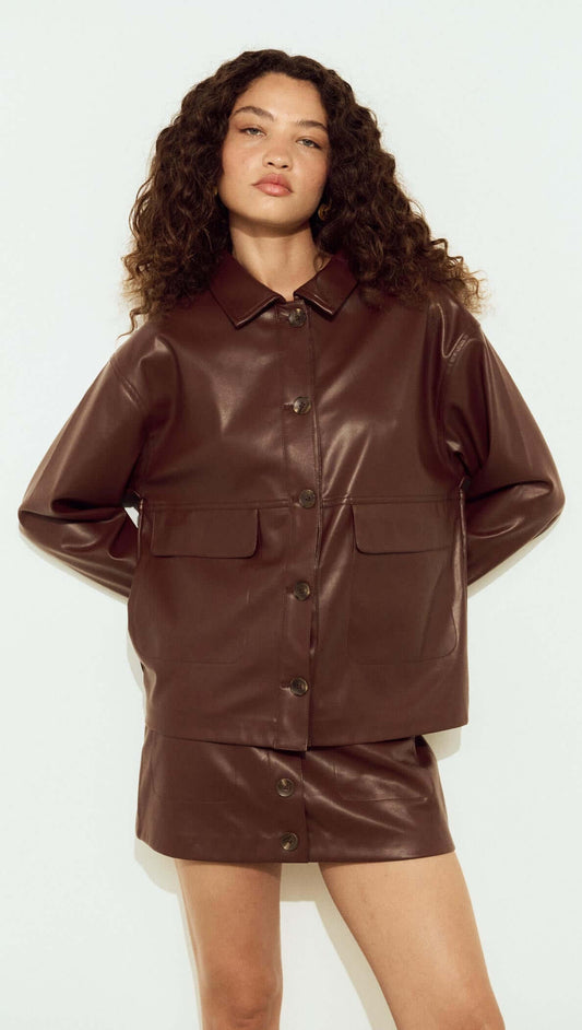 Model wearing a brown faux leather mini skirt and matching jacket, showcasing trendy fall fashion.
