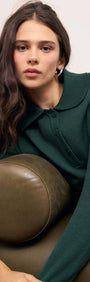 Model showcasing the Teal Green Knit Polo Sweater with a structured collar, relaxing on a green sofa.