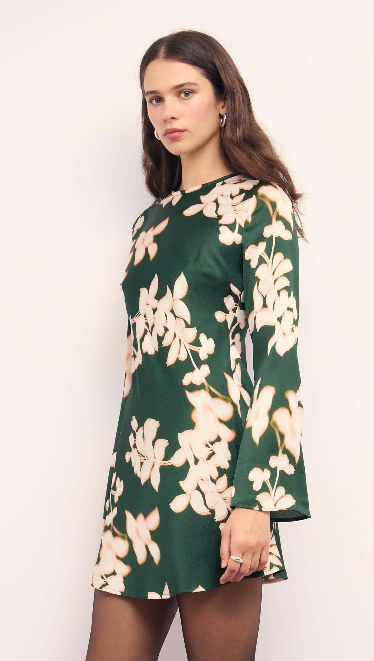 Green &amp; Cream Floral Satin Mini Dress displayed on a model with long sleeves and floral designs against a green background.