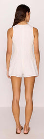 Back view of a woman wearing a White Cotton Jacquard Button-Up Playsuit, showcasing flared shorts and a comfortable fit.