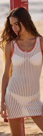 White Cotton Knit Mini Dress with Scallop Contrast Edge on the beach, showcasing airy crochet design and vibrant trim.