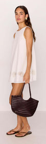 White Mini Shift Dress with Embroidered Shell Detail worn with a braided handbag and flip-flops.